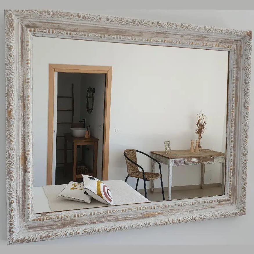Chambre Capraia : miroir à cadre patiné reflétant le lit, une table ancienne et la salle d'eau