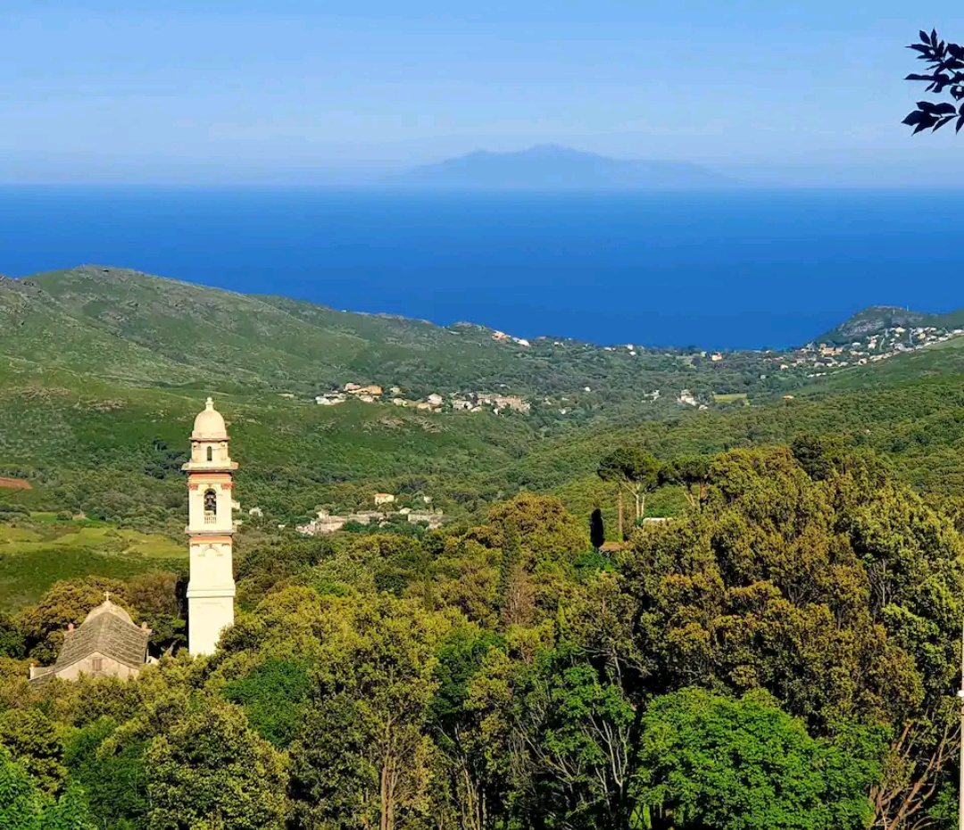Collines vertes et clocher blanc, avec la mer à l'horizon
